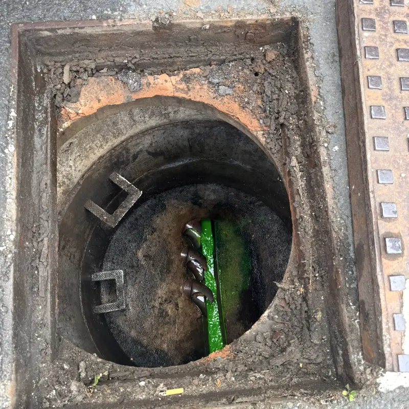 Green tracer dye visible in the channel of a separate manhole on another job